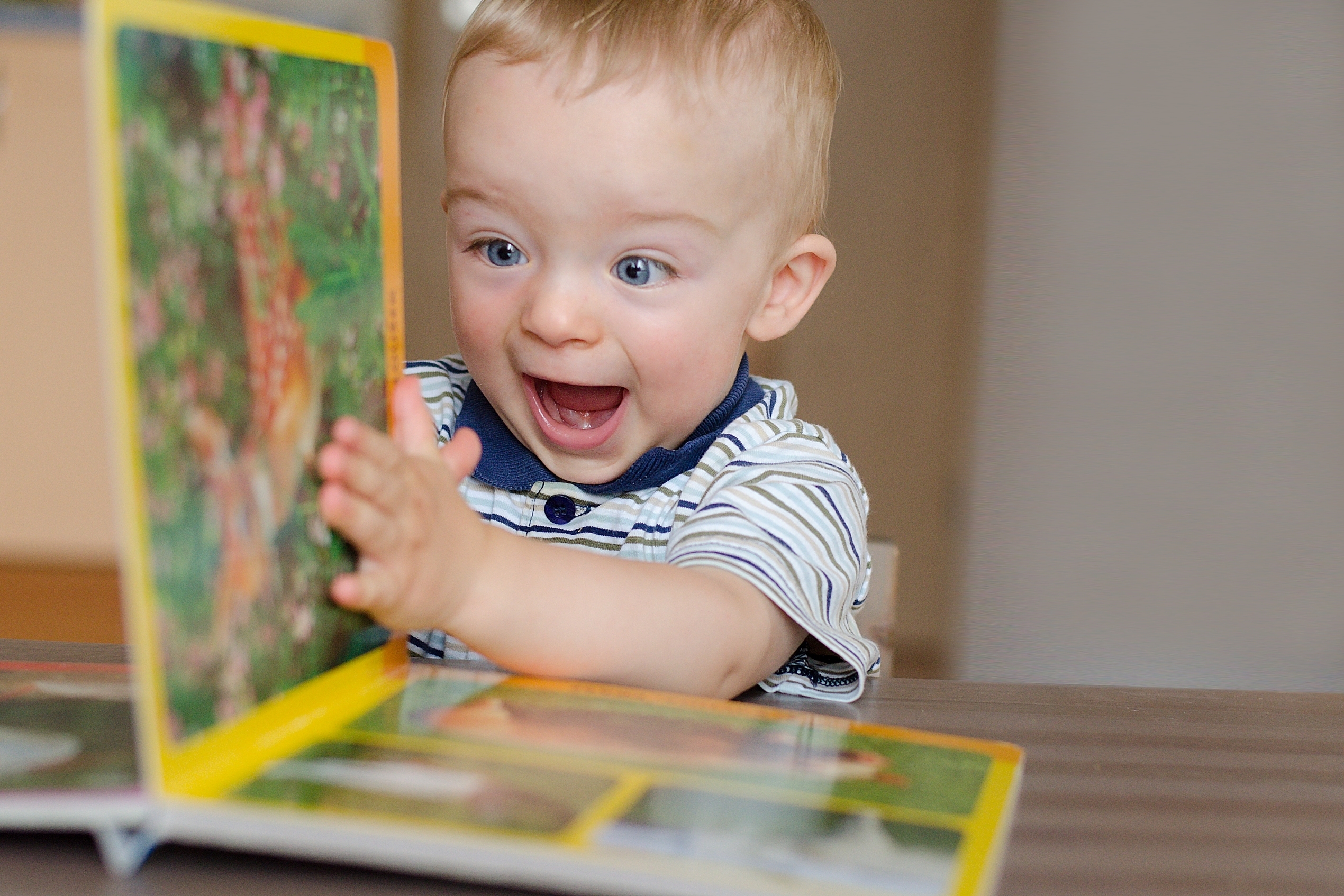 two boys sitting on striped rug reading a book together